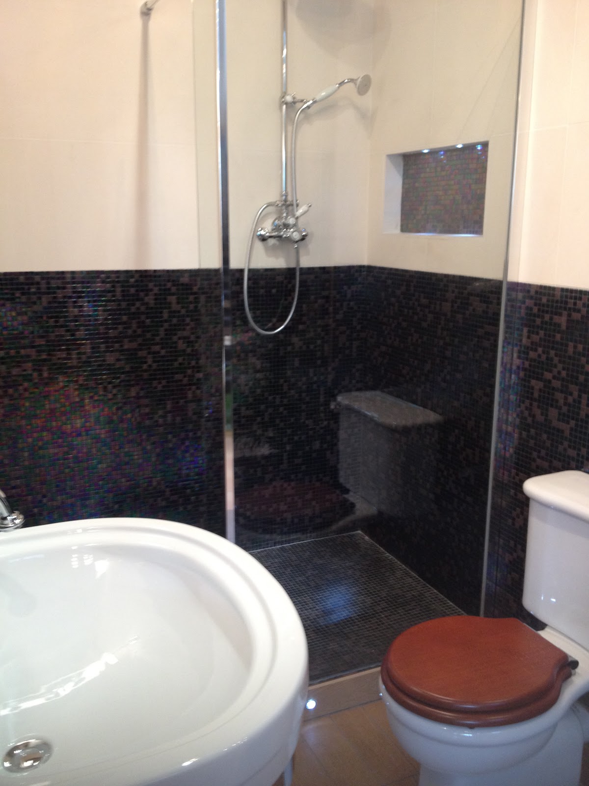 traditional bathroom accessories Wood effect flooring, mosaic shower area and built in shelf