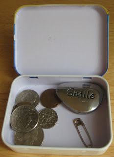 open tin container with coins and safety pin