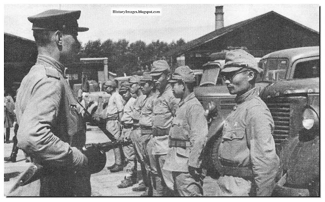 A Russian soldier stands guard over Japanese POWs