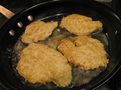 four chicken filets cooking in a pan