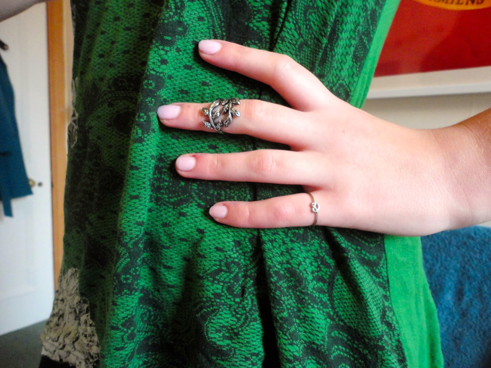 Green patterned top with hand wearing silver leaf & knot rings and pink nail polish