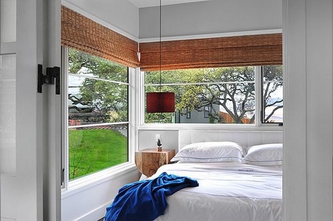 [A bedroom with a lot of large windows that create an illusion of sleeping in a garden]