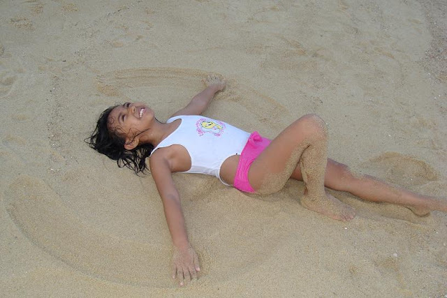 a child having fun in the sand and forming a beach angel