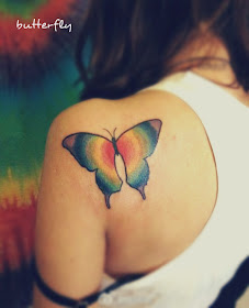 a butterfly tattoo on the back with colors of rainbow