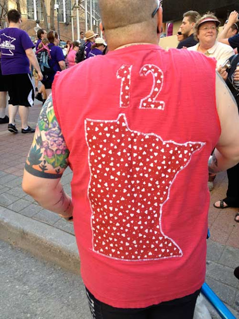 Man in hand-crafted red t-shirt with Minnesota quilted on with the number 12 above