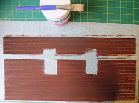 Two freshly-painted pieces of dolls' house miniature weatherboarding, with window holes cut out.