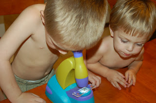 two boys looking in toy microscope