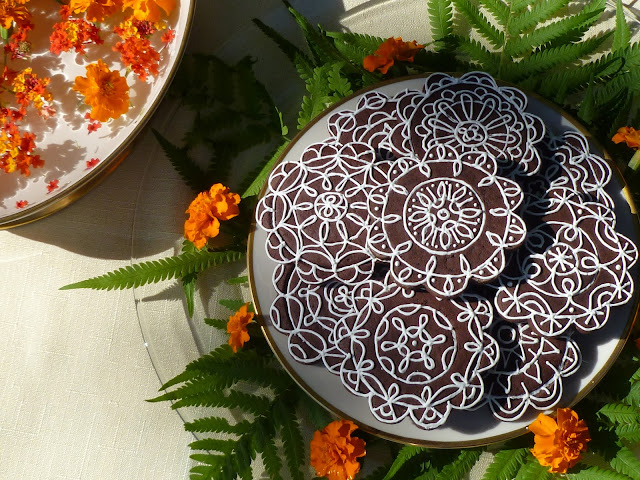beautifully decorated dark-chocolate tea biscuits with marigolds and fern fronds