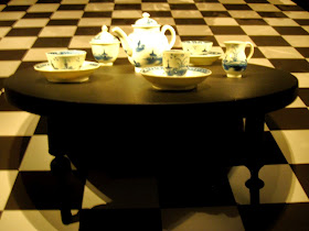 Miniature tea set on display in a museum, on a miniature antique table