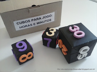 Três cubos pintados de preto, com 6 números em relevo (EVA) colados. Os dois menores representam as horas e o maior representa os minutos.