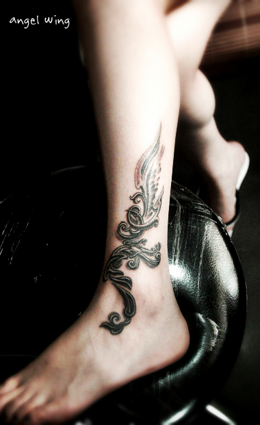 A black angel wing tattoo design on the ankle along with artistic letters