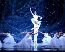 dancing ballaninas in white costumes around a ballarina held in the air by a man in the nutcracker ballet