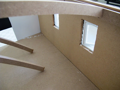 Inside of a half-built dolls' house shed, showing that the windows don't fit the full depth of the wall.
