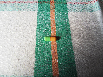 Green and orange capsule on tablecloth