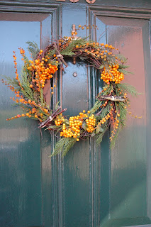 Yellow cotoneaster berries, mossy twig bundles and crocosmia seed heads decorate this pine and willow wreath.