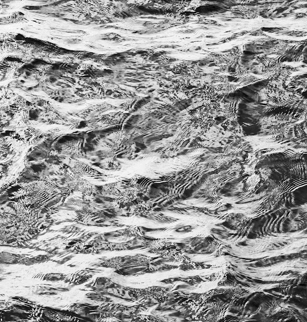 Monochrome of the sea where it hits rocks and returns against itself.