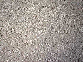 Scrapbooking paper embossed with a paisley and daisy pattern.