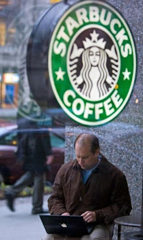 Un hombre con su portátil en la terraza de una cafetería de la cadena Starbucks.-