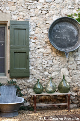 Dans un patio, mise en scène avec des vieilles bombonne et un ancien receveur de douche en zinc