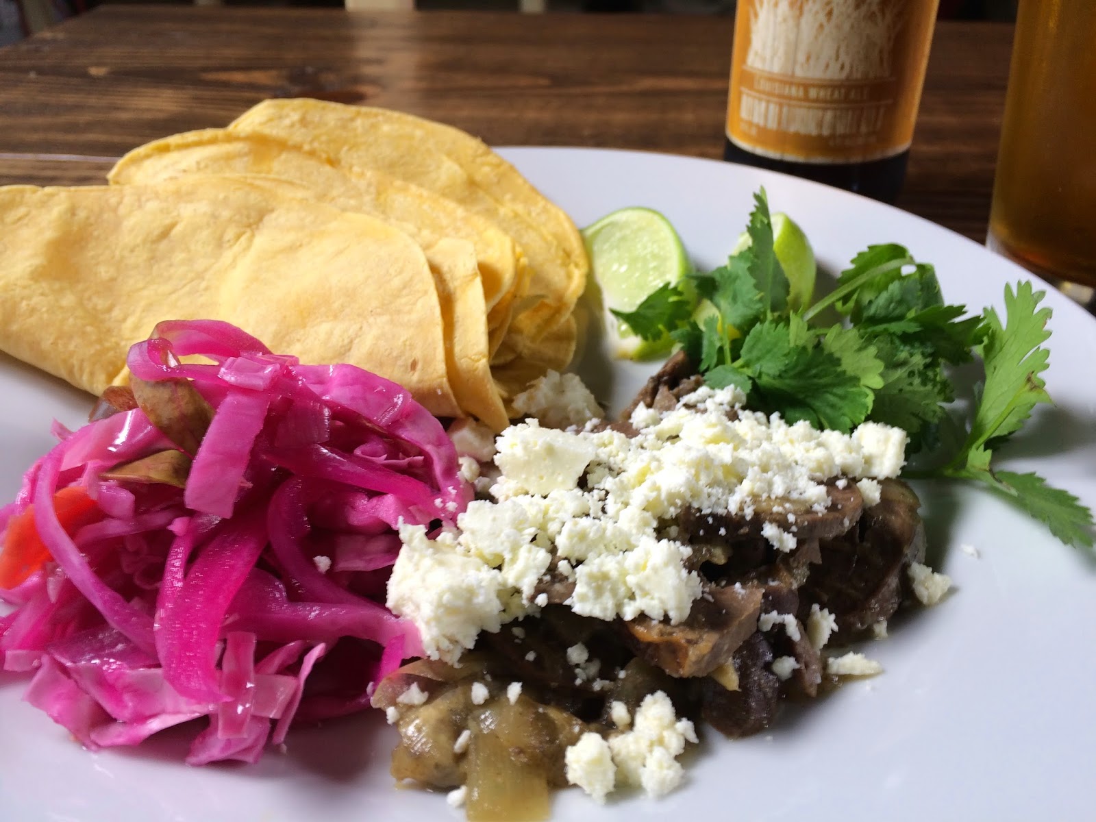 Braised Heart Taco: Slow Cooked Lamb Heart, Cilantro, Curtido, Lime, and Feta. Pictured with a Parish Brewing Co. Canebrake.