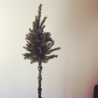 An artificial Christmas tree. The top section stands on a bare base.