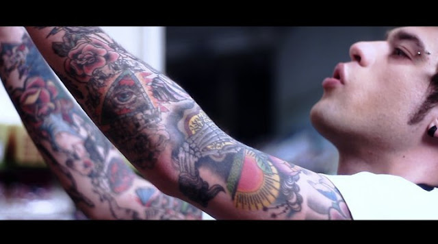 frame tratto dal suo videoclip Penisola che non c' fra i tatuaggi spunta