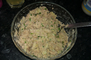 A bowl containing a mixture of salmon, potato, chive, lemon juice and mayonnaise ready to be formed into salmon fishcakes