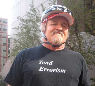 Man with black shirt, white letters, reading Tend Errorism