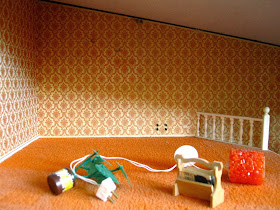 1975 Lundby dolls' house lounge, empty except for a pot plant, a magazine rack and an orange light.