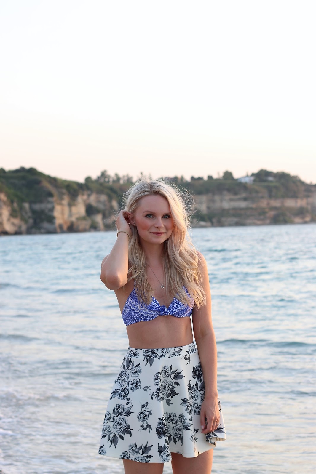 a blonde girl poses in front of beautiful sunset in italy on the beach