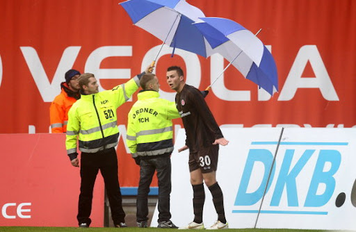 St Pauli player takes corner with umbrella protection St Pauli player takes corner with umbrella protection