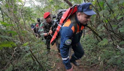 Seorang anggota TNI membantu seorang anggota tim Rusia saat mendaki Gunung Salak ke lokasi jatuhnya pesawat Sukhoi Superjet 100, Minggu (13/5). REUTERS/Jefri Tarigan Stamina Sukarelawan Dan Tim SAR Evakuasi Korban Sukhoi Menurun