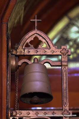 Small bronze door bell with cross on top.