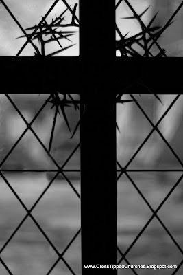 Black and white picture of silhouette of Cross with crown of thorns back lit with a diamonded patterned window.