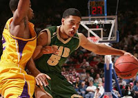 UAB basketball players number 5 dribbles during a game against a defender in a yello uniform.