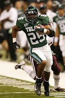 Ball carrier in a green Tulane uniform runs the football down the sideline in a football game.