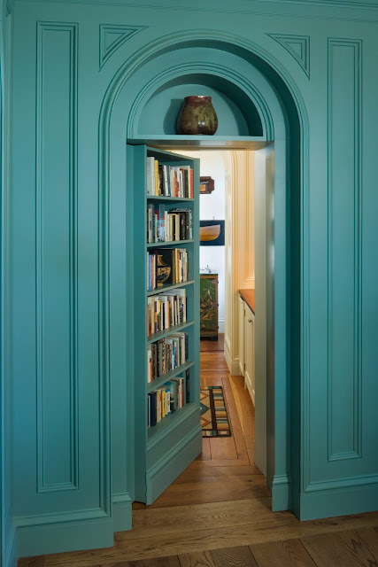 Teal bookshelf doubles as an arched secret library door by Peter Pennoyer