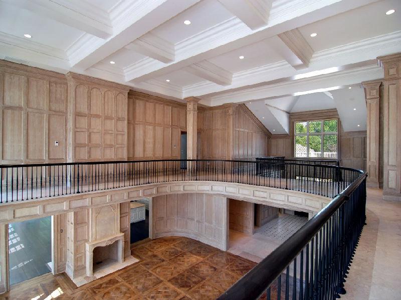 Second floor with light wood paneling, black railing and a coffered ceiling