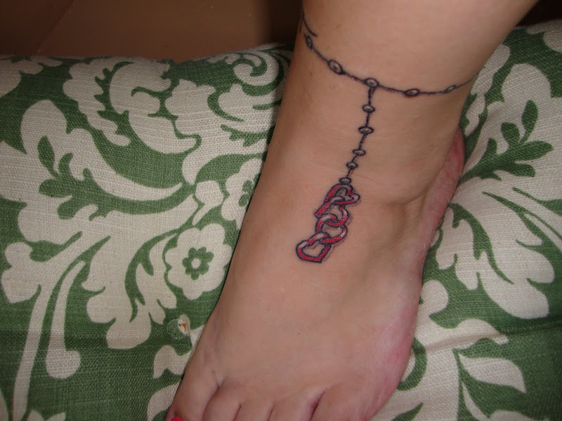 The tattoo wraps around like an ankle bracelet. The four hearts are my  title=