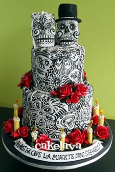 bride and groom skulls make the third layer in a black and white detailed cake with red roses on it
