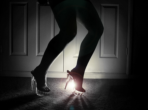 Image of woman's legs and feet, backlit, wearing high heels