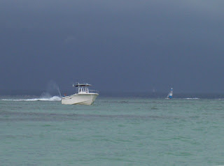 White boat in green-blue waters with dark storm cloud behind, Florida