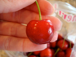 Hand holding cherry by stem