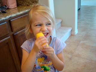 Young girl eating a piece of corn off cob