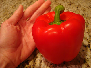 Hand next to a large red bell pepper