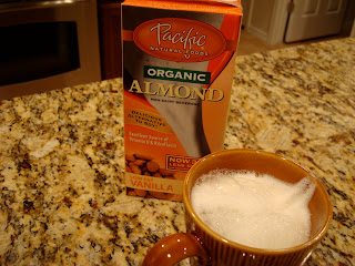 Brewed Coffee in mug topped with almond milk and almond milk container in background