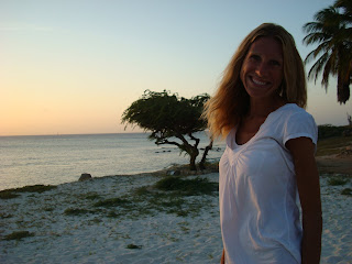 Woman standing on beach at sunset smiling