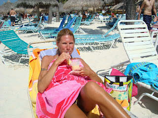 Woman on lounger covered up with towel drinking a drink