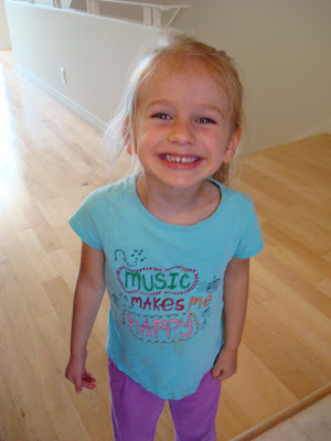 Young girl in blue shirt standing smiling 