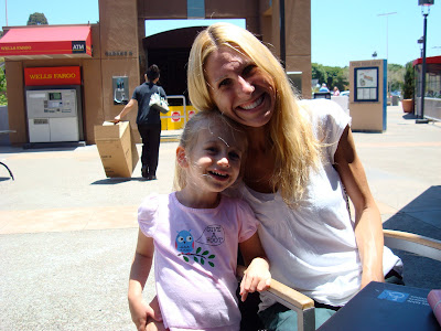 Woman sitting in chair with young girl at her side smiling